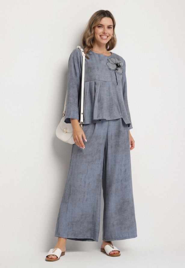 Niebieski Komplet Bluzka z Rozkloszowanym Dołem i Aplikacją Kwiatka i Luźne Spodnie Ravirisa
